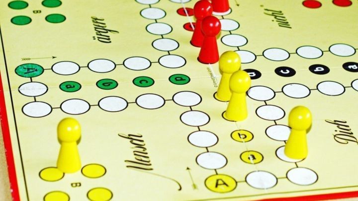 Auf dem Spielbrett von Mensch &auml;rgere dich nicht stehen gelbe und rote Spielsteine in verschiedenen Positionen.