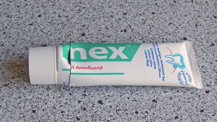 Eine Zahnpasta-Tube liegt auf einer grauen Oberfl&auml;che, bereit zum Benutzen, um die Z&auml;hne zu reinigen und zu pflegen.