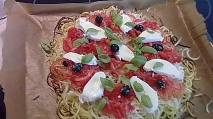 Zucchini-Spaghetti werden in einer Sch&uuml;ssel pr&auml;sentiert, gefolgt von einer gebackenen Gem&uuml;se-Pizza mit K&auml;se und Tomatensauce.