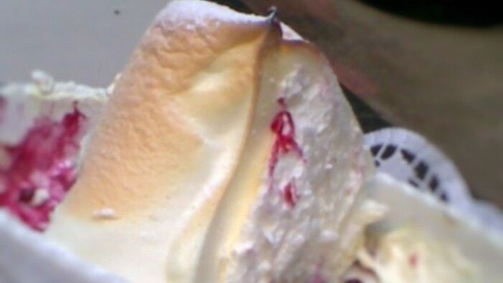 Zarte Salzburger Nockerl liegen auf einem Teller, umgeben von Sahne und einem L&ouml;ffel in einem gem&uuml;tlichen Ambiente.