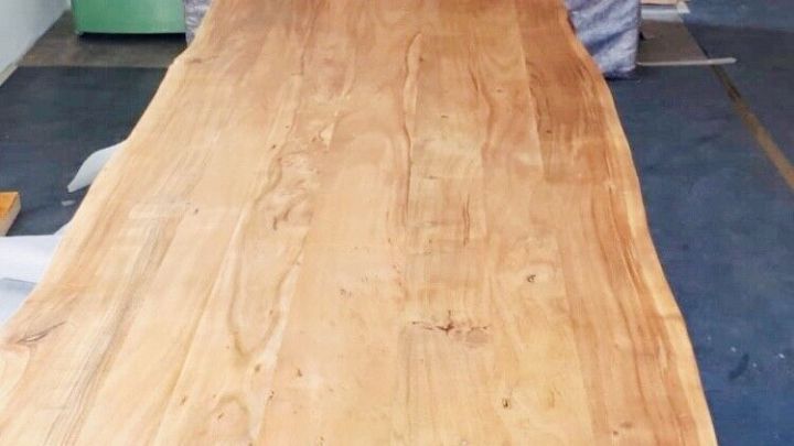 Ein handgefertigter Holztisch wird in einer Werkstatt bewegt, um Wasserflecken auf der Oberfl&auml;che zu entfernen.