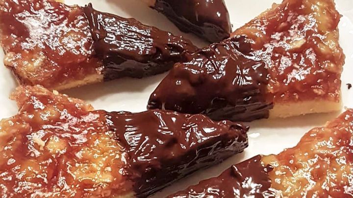 Ein Teller mit Nussecken liegt auf einem Tisch, die mit einer gl&auml;nzenden Schokoladenglasur &uuml;berzogen sind.