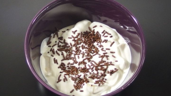 Eine Sch&uuml;ssel Quarkspeise steht auf einem schwarzen Tisch, dekoriert mit Schokoladenstreuseln.