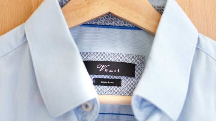 Ein b&uuml;gelfreies Hemd h&auml;ngt auf einem Holzkleiderb&uuml;gel, bereit zum Tragen in einem modernen Kleiderschrank.