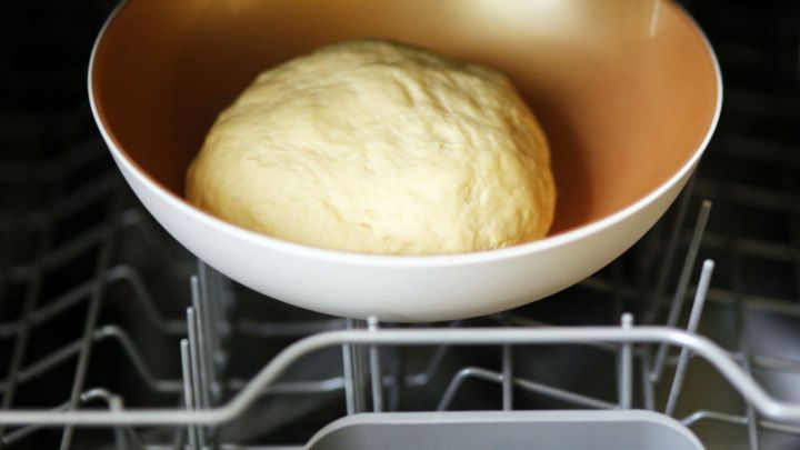 Ein Hefeteig liegt in einer Sch&uuml;ssel, die in einer offenen, warmen Sp&uuml;lmaschine positioniert ist, um zu gehen.