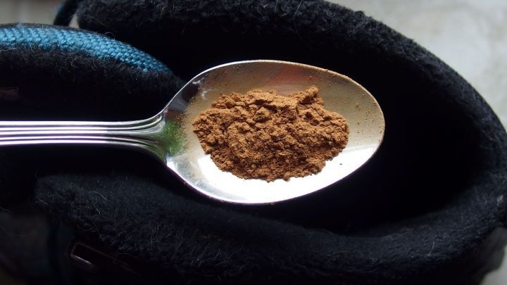 Ein L&ouml;ffel mit Zimt liegt auf einem schmutzigen Turnschuh und soll helfen, schlecht riechende Schuhe zu neutralisieren.