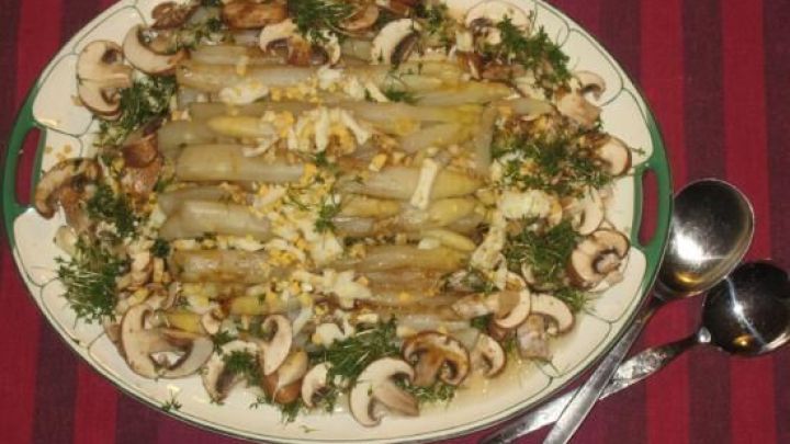 Ein Salat aus frischen Champignons und Spargel ist auf einer wei&szlig;en Platte angerichtet, umgeben von Kresse und Ei.
