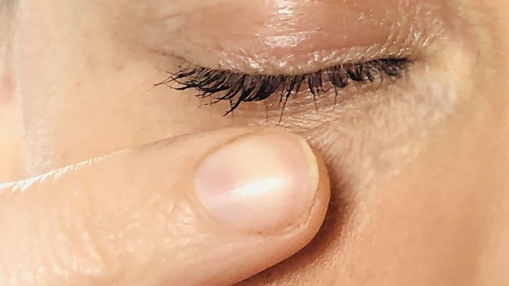 Eine Hand zeigt vorsichtig auf das Auge, um einen Fremdk&ouml;rper zu entfernen, w&auml;hrend der Hintergrund unscharf bleibt.