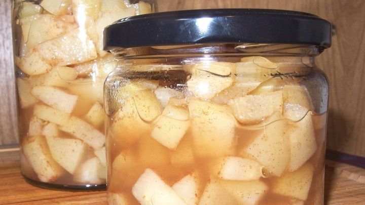 Glasbeh&auml;lter mit st&uuml;ckigen, eingelegten &Auml;pfeln in s&uuml;&szlig;er Fl&uuml;ssigkeit stehen auf einer Holzfl&auml;che, die Zucker ersetzen k&ouml;nnen.