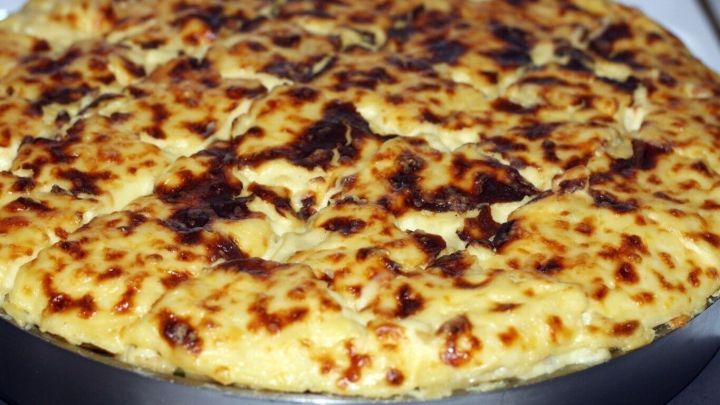 Ein goldbraun gebackener Auflauf in einer runden Backform steht auf einer K&uuml;chenarbeitsplatte und wartet darauf, eingefroren zu werden.