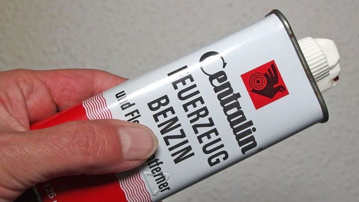 Eine Hand h&auml;lt eine Dose mit Feuerzeugbenzin, die zur Entfernung von Kleberesten von der Haut verwendet wird.