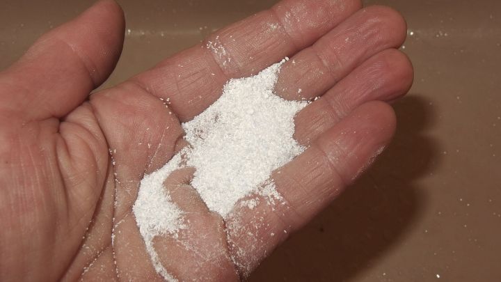 Wei&szlig;e Sp&uuml;lmaschinenreiniger-Pulver liegt in einer Hand, bereit f&uuml;r die Reinigung fett-/&ouml;lverschmutzter H&auml;nde in der K&uuml;che.