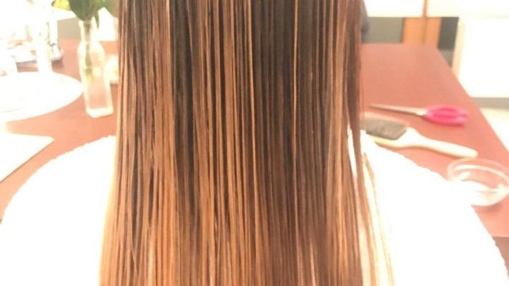 Langes, glattes Haar f&auml;llt frei nach unten und zeigt Br&uuml;nettt&ouml;ne mit ombr&eacute; Effekten, in einem hellen, wohnlichen Raum.