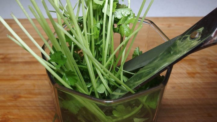 Ein Glas mit frischer Petersilie wird mit einem Messer geschnitten, um sie schnell und einfach f&uuml;r die K&uuml;che vorzubereiten.