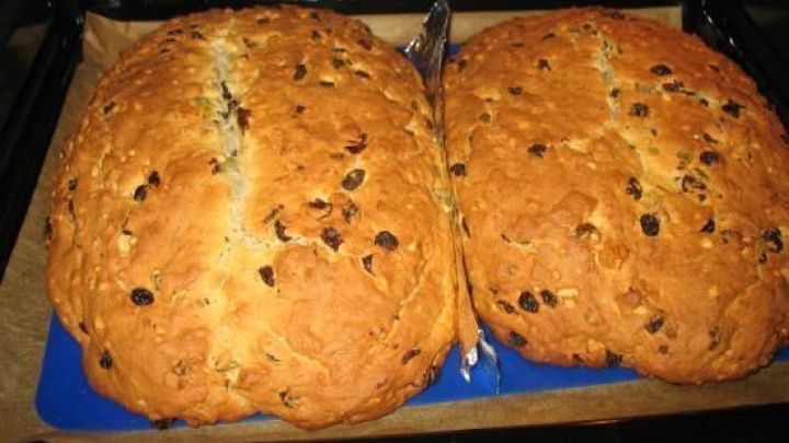Zwei goldbraune, stollen&auml;hnliche Geb&auml;ckst&uuml;cke mit Rosinen und N&uuml;ssen backen nebeneinander im offenen Ofen auf einem Blech.