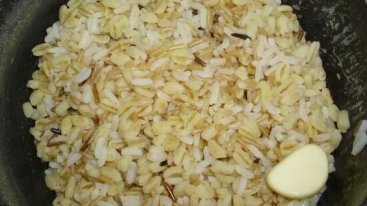 Eine Mischung aus verschiedenen Reissorten wird in einem Topf mit Butter erhitzt, um ein schmackhaftes Gericht zu kreieren.