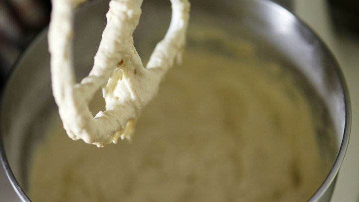 Ein R&uuml;hrger&auml;t h&auml;lt einen Teig f&uuml;r Ausstecherle &uuml;ber einer silbernen Sch&uuml;ssel, umgeben von einer K&uuml;chenumgebung.