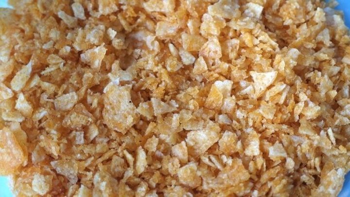 Zerkleinerte Corn Flakes liegen auf einem Teller, bereit zum Panieren von Schnitzeln in einer K&uuml;che.