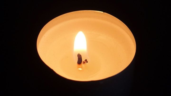 Eine brennende Kerze leuchtet hell, w&auml;hrend der abgebrochene Docht mit einem Holz-Zahnstocher stabilisiert wird.