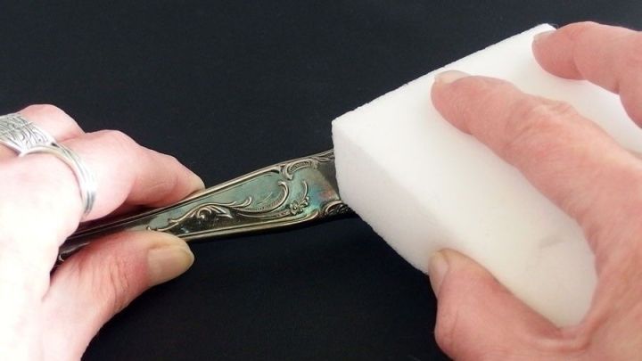 Ein St&uuml;ck Silberbesteck wird mit einem Schmutzradierer gereinigt. Die H&auml;nde halten den L&ouml;ffel und den Radierer.
