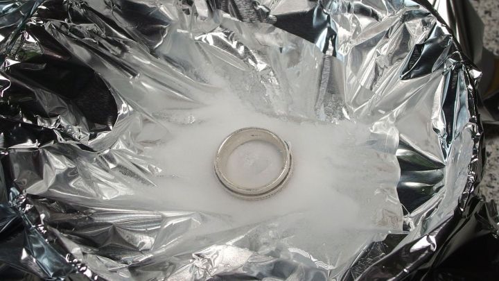 Ein silberner Ring liegt auf einem Aluminiumfolie-Boden, um mit Natron gereinigt zu werden.