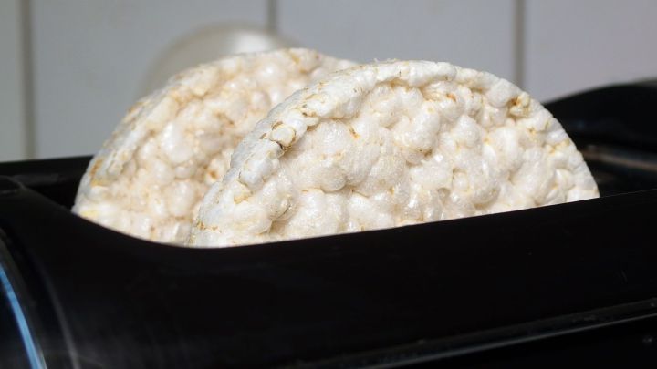 Reiswaffeln werden im Toaster erhitzt und nehmen dabei eine knusprige Form an. Hintergrund ist eine moderne K&uuml;che.