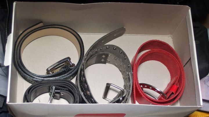 Schuhkarton im Kleiderschrank enth&auml;lt ordentlich gefaltete G&uuml;rtel in verschiedenen Farben und Materialien f&uuml;r gute Ordnung.