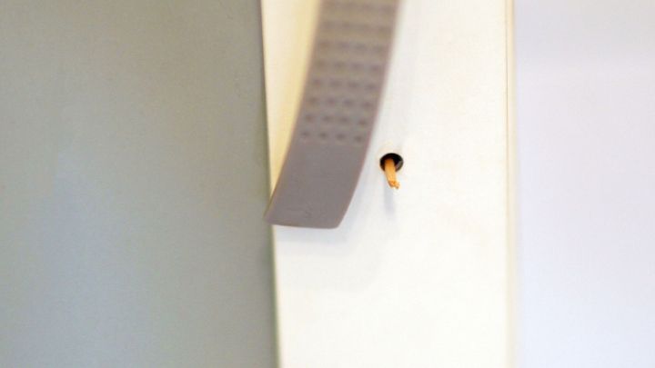 Ein grauer Griff h&auml;ngt locker am Schrank und ber&uuml;hrt einen kleinen Holzstift in einem Loch der Schrankt&uuml;r.