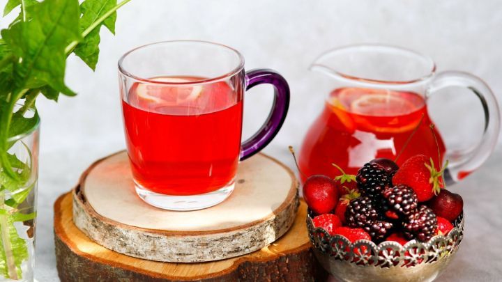 Ein Glas fruchtiger Durstl&ouml;scher steht auf einem Holzuntersetzer, w&auml;hrend ein Krug neben frischen Beeren platziert ist.