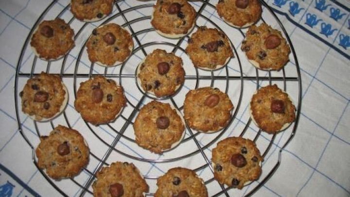 Saftige Hafer-Nuss-Makronen ruhen auf einem Gitter, um abzuk&uuml;hlen, umgeben von einem wei&szlig;en K&uuml;chentuch mit blauem Muster.