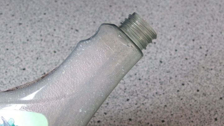 Eine Flasche mit einem leicht ge&ouml;ffneten Deckel steht auf einer strukturierten Oberfl&auml;che, bereit f&uuml;r selbstgemachte Putzmittel.