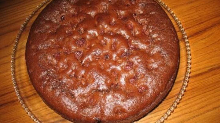 Eine runde Schoko-Kirsch-Torte liegt auf einem dekorativen Teller aus Glas und wartet, serviert zu werden.