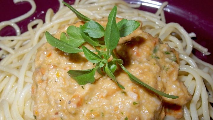 Eine cremige Basilikum-Tomaten-Sauce liegt auf einem Bett aus Spaghetti, dekoriert mit frischem Basilikum.