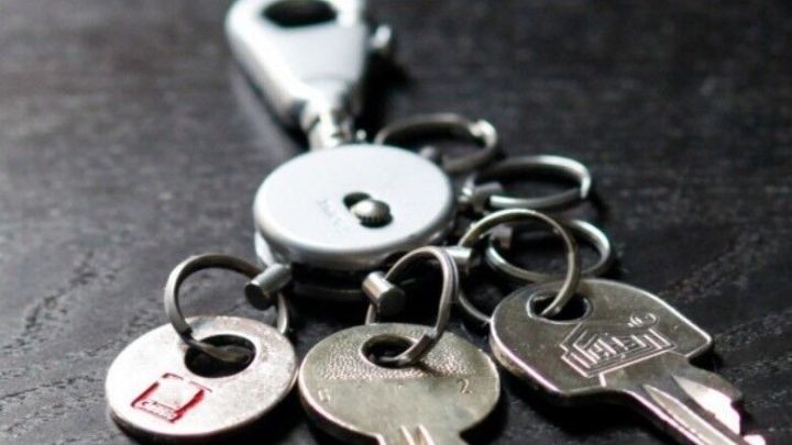 Ein Schl&uuml;sselbund mit einem Rundzylinder und mehreren Schl&uuml;sseln liegt auf einer dunklen Oberfl&auml;che, bereit zur Verwendung.