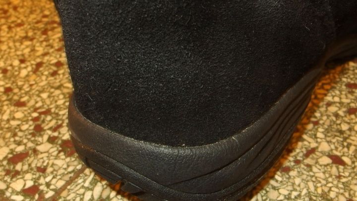 Schwarzer Wildlederschuh auf einem glatten Boden, der auf einen Polster-/Matratzenreiniger ausgerichtet ist.