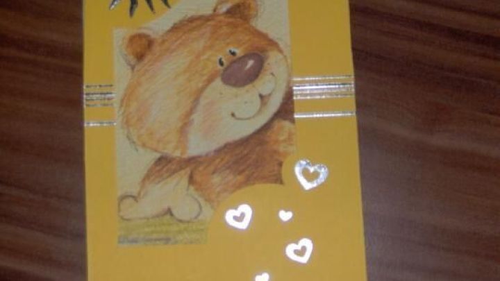 Eine Karte zeigt einen l&auml;chelnden B&auml;ren mit Goldherzen und einem Spiralenschmuck auf gelbem Hintergrund, ideal zum Gestalten.