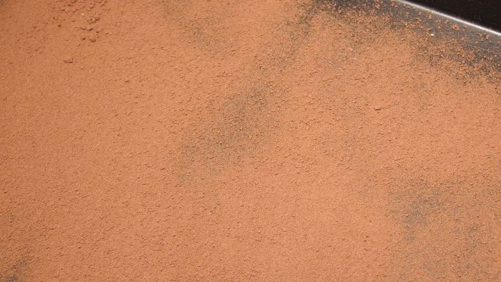 Ein Blech ist mit einer gleichm&auml;&szlig;igen Schicht Kakao bedeckt, bereit zum Backen an einem dunklen Arbeitsplatz.