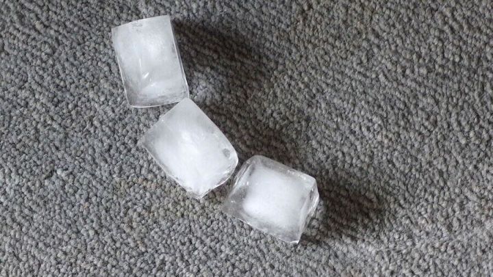 Eisw&uuml;rfel liegen auf einem Teppich, wo sie schmelzen und Druckstellen im Teppich verhindern sollen.