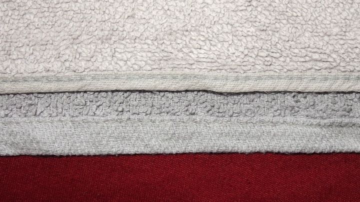 Dicke Handt&uuml;cher liegen &uuml;bereinander, w&auml;hrend zwei St&uuml;cke zusammen gen&auml;ht werden, um ein gr&ouml;&szlig;eres Handtuch zu kreieren.