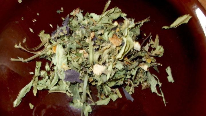 Getrocknete Kr&auml;uter liegen auf einem braunen Teller. Sie sind klein geschnitten und wirken aromatisch und w&uuml;rzig.