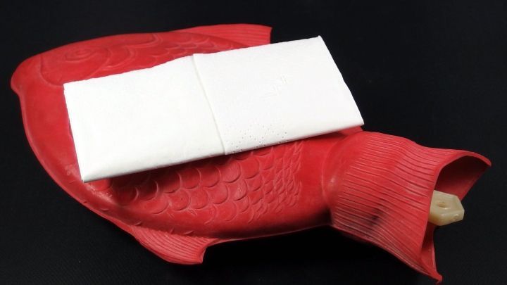 Ein rotes Ohrensp&uuml;lsystem liegt auf einer schwarzen Oberfl&auml;che und bereitet sich darauf vor, Ohrenschmalzpfropfen zu entfernen.