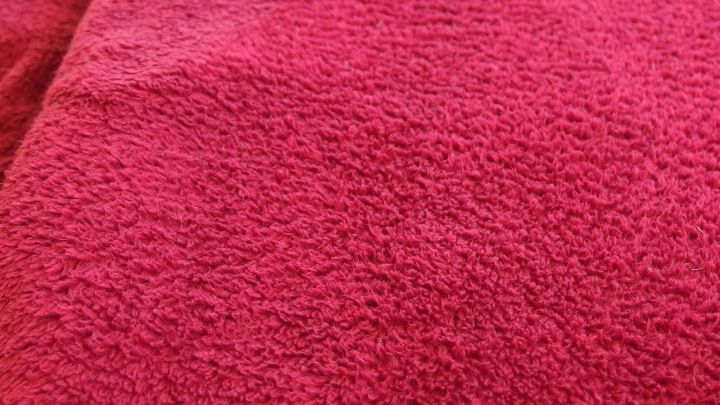 Flauschige Wohndecke in leuchtendem Rot, die locker und weich aussieht, ist auf einer flachen Oberfl&auml;che drapiert.