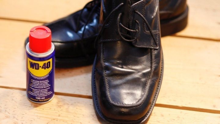 Schwarze Lederschuhe stehen auf einem hellen Holzboden, neben einer WD-40-Dose zur Impr&auml;gnierung.
