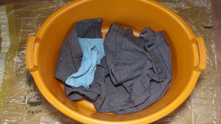 Eine Plastikt&uuml;te sch&uuml;tzt die herunterfallende W&auml;sche in einer orangefarbenen Sch&uuml;ssel auf einem Untergrund.