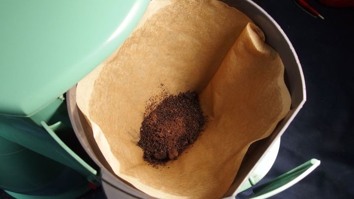 Ein Kaffeefilter mit Kaffeesatz liegt in einem Beh&auml;lter, bereit zur zweiten Verwendung im K&uuml;chenumfeld.