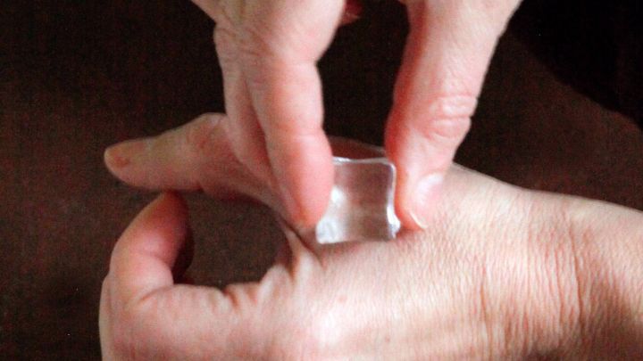 Mit einer Hand wird ein kleines, durchsichtiges Objekt auf die andere Hand gedr&uuml;ckt, um m&ouml;glicherweise Zahnschmerzen zu lindern.