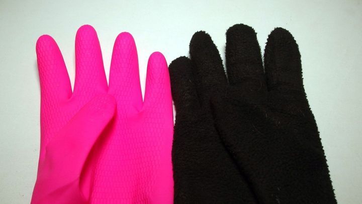 Zwei Paar Handschuhe, ein pinkes und ein schwarzes, liegen nebeneinander auf einem wei&szlig;en Hintergrund, ideal gegen kalte H&auml;nde.