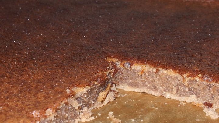 Ein Schokokuchen liegt auf einem Tisch, leicht angeschnitten und gl&auml;nzend, umgeben von einer warmen, einladenden Atmosph&auml;re.