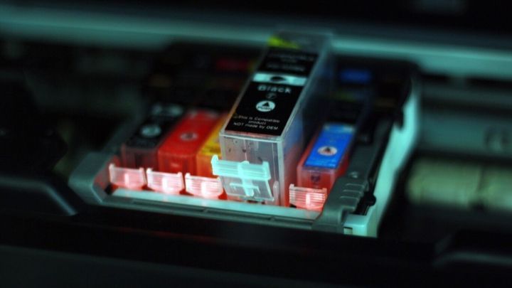 Eine Druckerpatrone leuchtet, w&auml;hrend sie in der Halterung sitzt, umgeben von weiteren Patronen im Dunkeln.