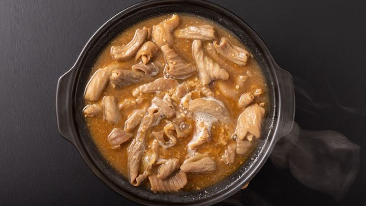 Ein schwarzer Topf enth&auml;lt dampfendes, zartes Fleisch in einer w&uuml;rzigen Br&uuml;he, bereit zum Verzehr in einem gem&uuml;tlichen Umfeld.